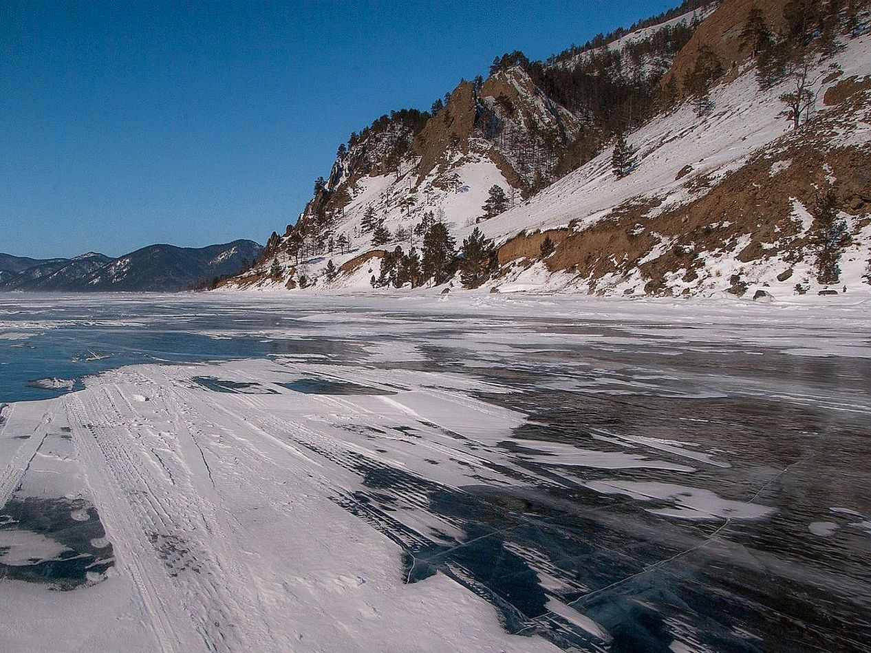 Um lago raso sobre pedras claras cobertas de neve